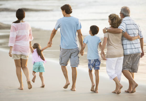 multi-generation-family-holding-hands-on-beach